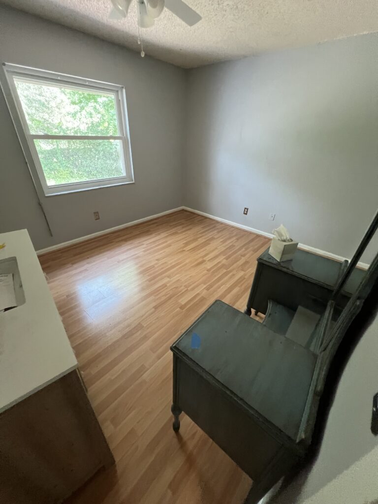 Bedroom with a clear wood floor, a window, and a dresser and mirror against the wall.