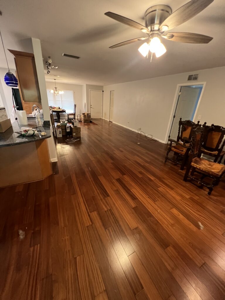 Living room with a broad clear wood floor, chairs along one wall, and a kitchen counter at the side.